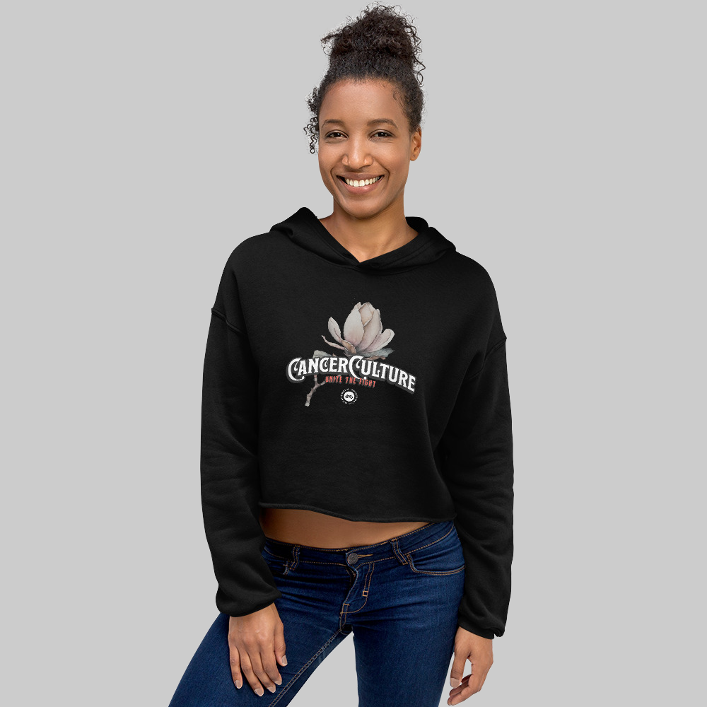 CancerCulture® Bloom Women's Crop Hoodie, Black, front, CancerCulture magnolia, Unite the Fight print, worn by woman, studio gray background